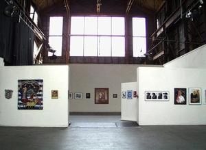 Wide angle image of a gallery with white walls and photographs