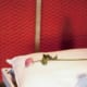 White pillow with pink rose lying across it against chicken wire background and red wall
